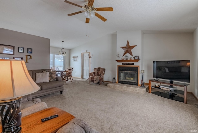 carpeted living room featuring lofted ceiling, a textured ceiling, a tiled fireplace, and ceiling fan with notable chandelier