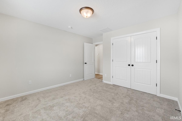 unfurnished bedroom with a closet, light colored carpet, and baseboards