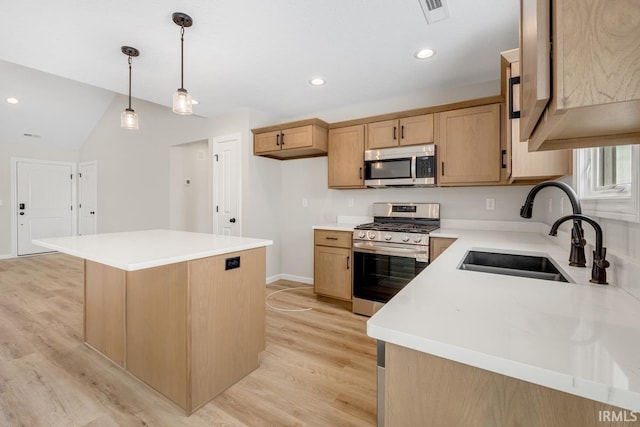 kitchen featuring stainless steel appliances, a sink, a kitchen island, light countertops, and decorative light fixtures