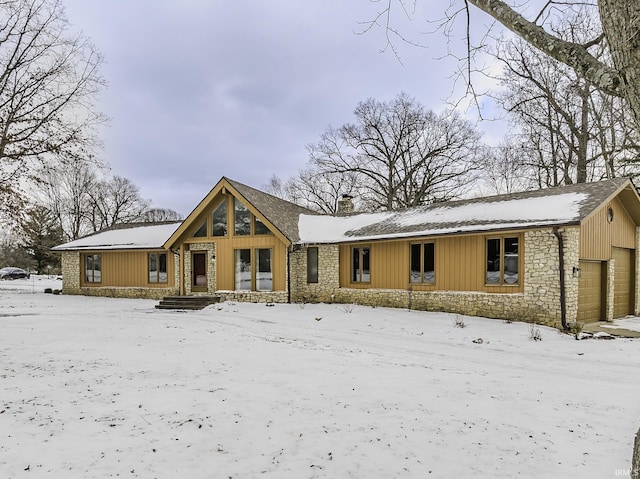 view of front of home with stone siding, a chimney, and board and batten siding