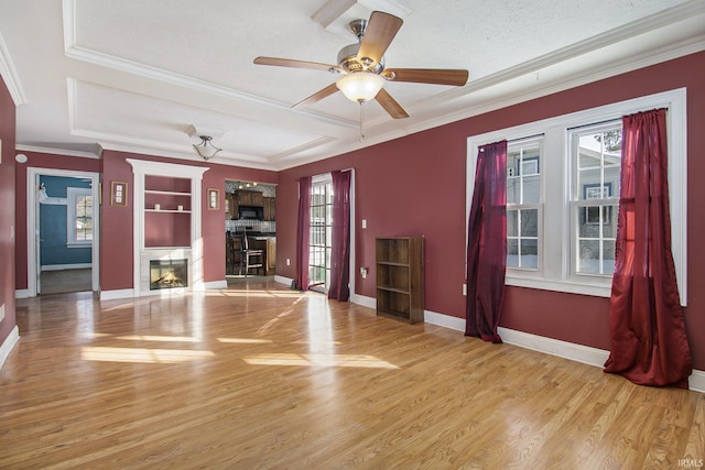 unfurnished living room featuring light wood-style floors, a glass covered fireplace, crown molding, and baseboards