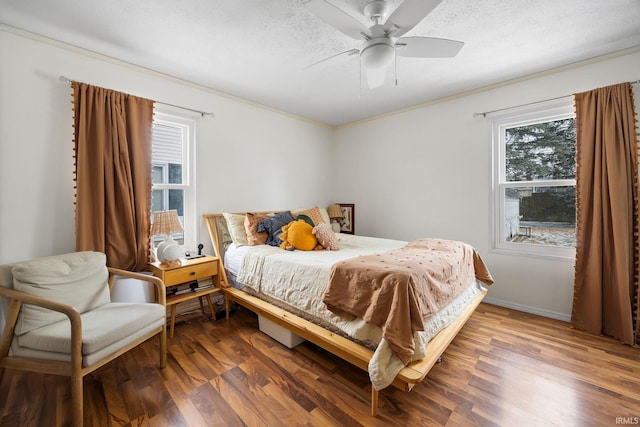 bedroom featuring a textured ceiling, dark wood-style flooring, a ceiling fan, baseboards, and ornamental molding