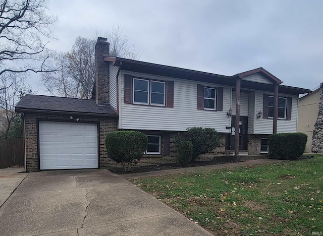 split foyer home with brick siding, a chimney, a garage, driveway, and a front lawn