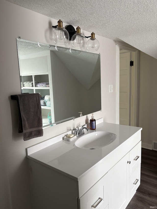 bathroom with visible vents, wood finished floors, a textured ceiling, and vanity