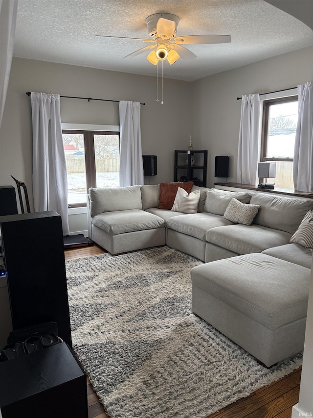 living area with a ceiling fan, a textured ceiling, and wood finished floors