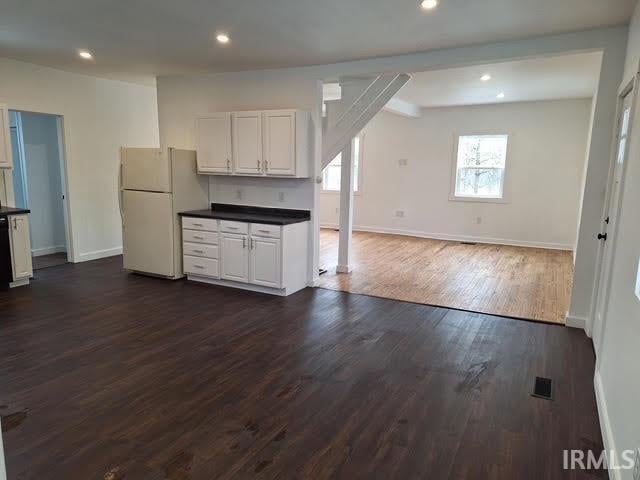 kitchen with open floor plan, dark countertops, freestanding refrigerator, and white cabinets