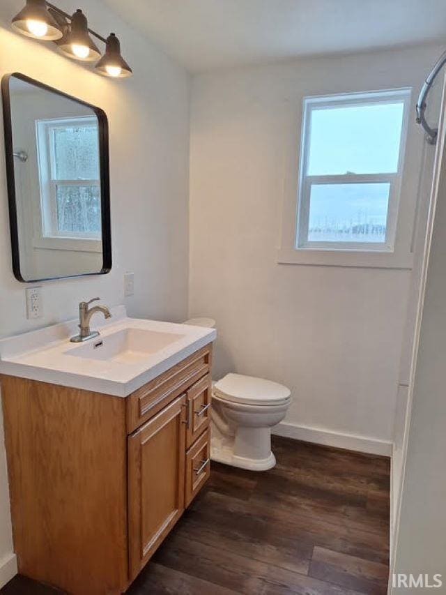 bathroom featuring toilet, plenty of natural light, wood finished floors, and vanity