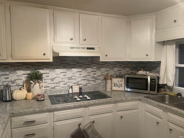 kitchen with stainless steel microwave, under cabinet range hood, black electric stovetop, and white cabinetry