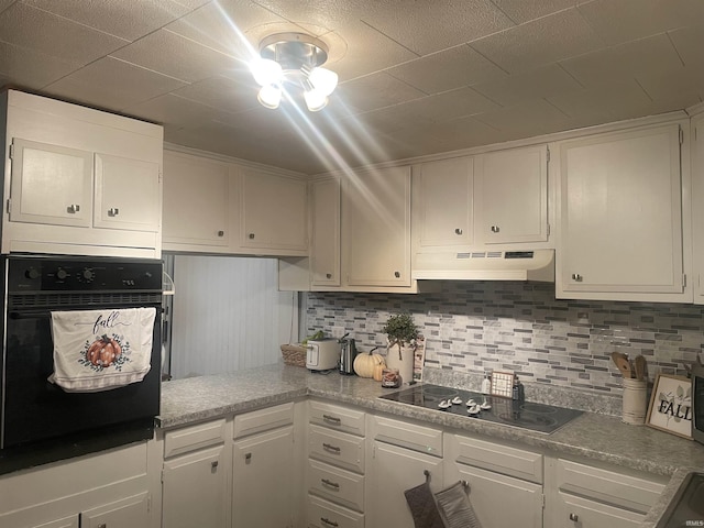 kitchen featuring decorative backsplash, white cabinetry, under cabinet range hood, and black appliances