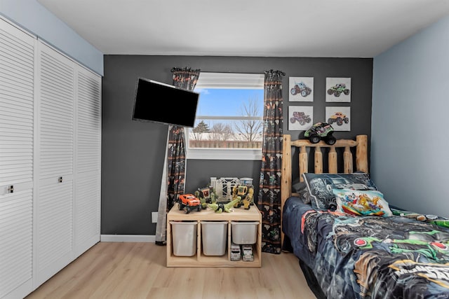 bedroom featuring light wood-style floors, baseboards, and a closet