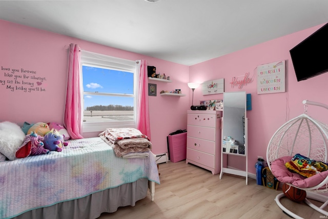 bedroom with a baseboard heating unit and light wood-style flooring