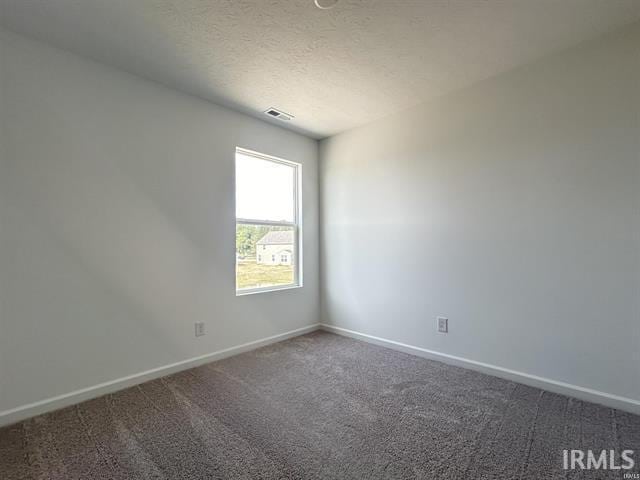 unfurnished room with carpet, visible vents, baseboards, and a textured ceiling