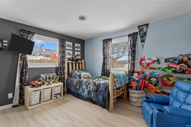 bedroom featuring multiple windows, light wood-type flooring, visible vents, and baseboards