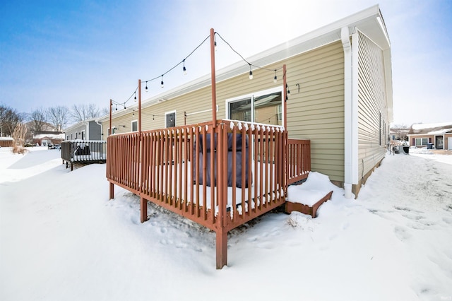 snow covered rear of property with a wooden deck