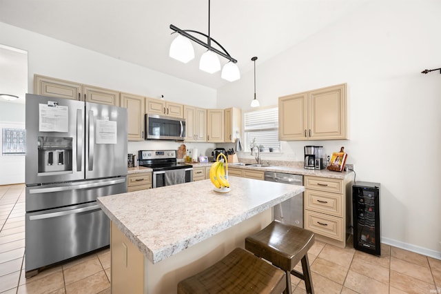 kitchen with appliances with stainless steel finishes, light countertops, decorative light fixtures, and a center island