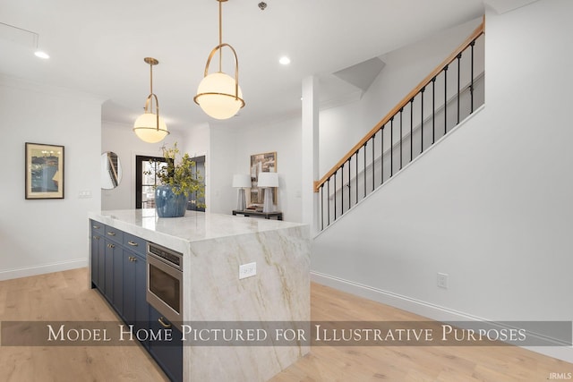 kitchen with hanging light fixtures, light stone counters, a kitchen island, and light wood-style floors