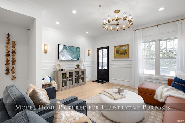 living area featuring ornamental molding, light wood-style floors, a decorative wall, a notable chandelier, and recessed lighting