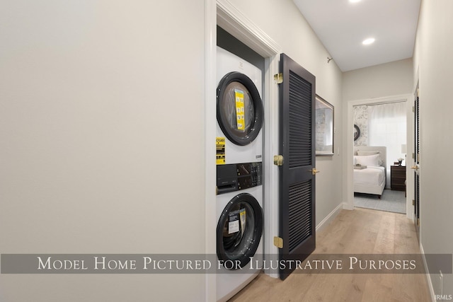 washroom featuring laundry area, light wood finished floors, baseboards, stacked washer / drying machine, and recessed lighting