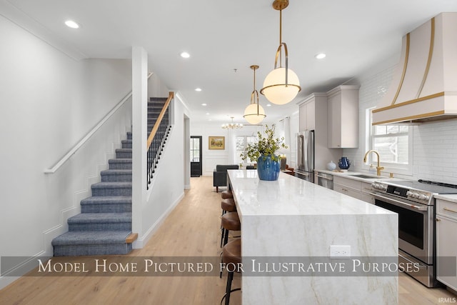 kitchen with appliances with stainless steel finishes, a center island, pendant lighting, and premium range hood