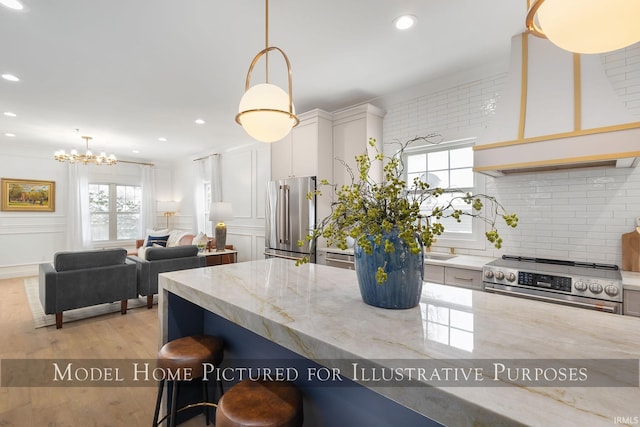 kitchen with hanging light fixtures, light stone countertops, appliances with stainless steel finishes, and white cabinets