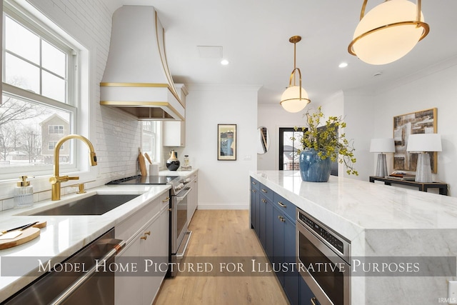 kitchen featuring blue cabinets, a sink, white cabinetry, decorative light fixtures, and custom range hood