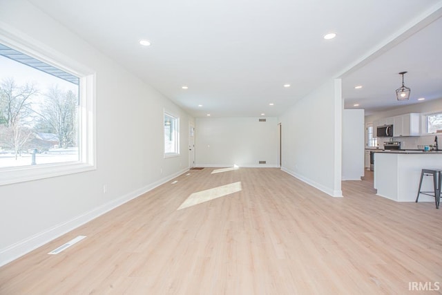 unfurnished living room featuring visible vents, recessed lighting, light wood-style flooring, and baseboards