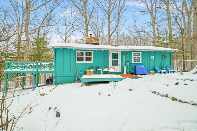 view of front of house with board and batten siding, fence, a chimney, and a deck