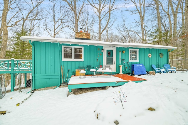 view of front of home featuring board and batten siding, a chimney, and a deck