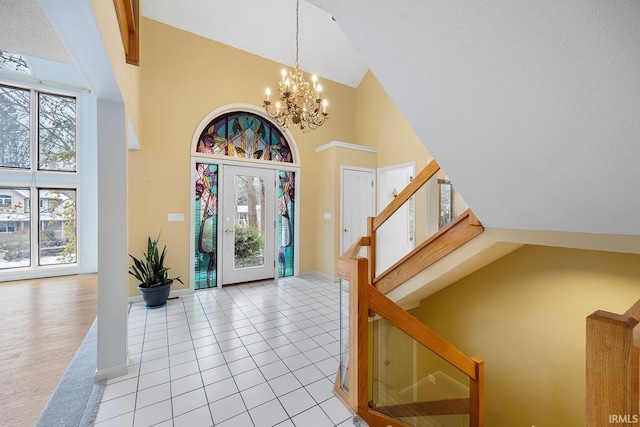 foyer entrance with light tile patterned floors, stairs, high vaulted ceiling, and a chandelier