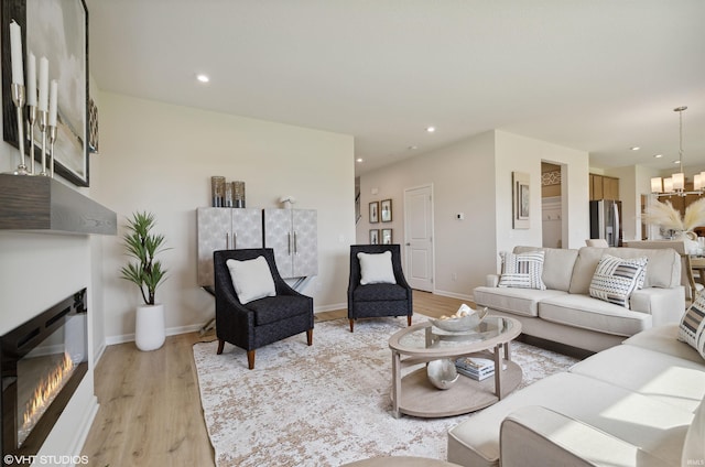 8973 Belmont Woods, Fort Wayne, IN 46835 - living area featuring baseboards, a glass covered fireplace, light wood-type flooring, a notable chandelier, and recessed lighting