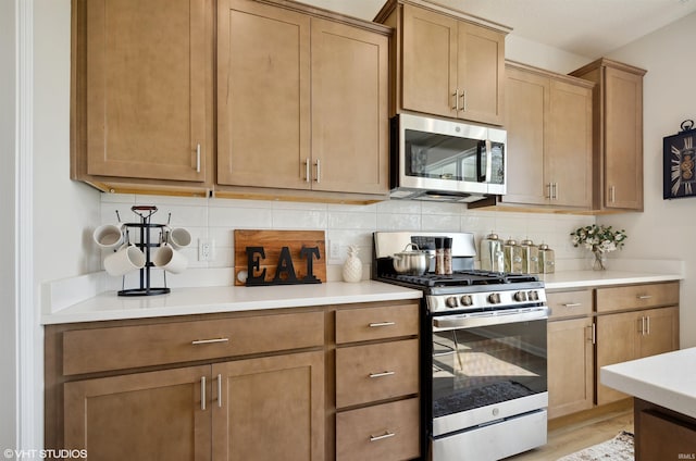 8973 Belmont Woods, Fort Wayne, IN 46835 - kitchen with stainless steel appliances, light wood finished floors, backsplash, and light countertops