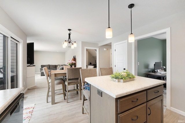 kitchen with light wood-style flooring, open floor plan, a center island, decorative light fixtures, and light countertops