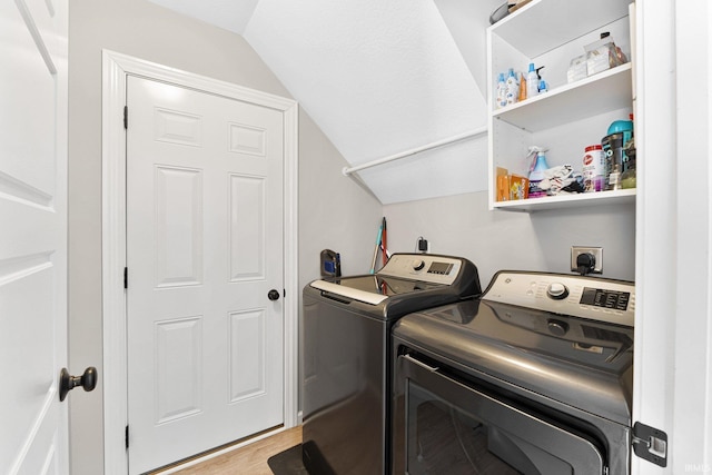 clothes washing area with laundry area, washing machine and clothes dryer, and light wood-style floors