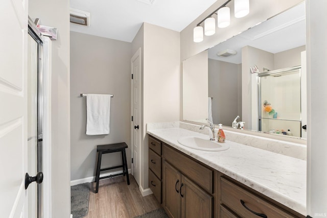 bathroom featuring a stall shower, vanity, baseboards, and wood finished floors