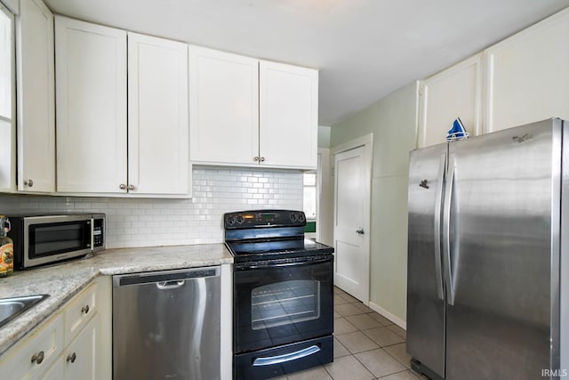 kitchen with white cabinets, light tile patterned floors, stainless steel appliances, and backsplash