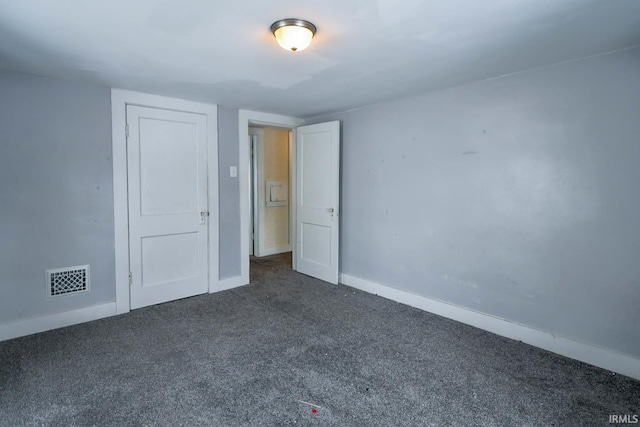 unfurnished room featuring dark colored carpet, visible vents, and baseboards