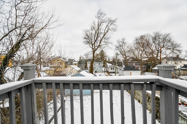 snow covered back of property featuring a residential view