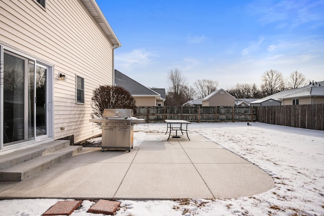 snow covered patio with entry steps, a fenced backyard, and a grill