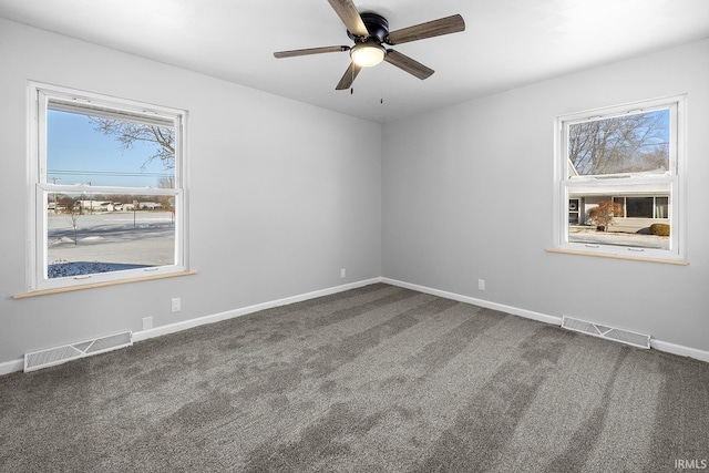 spare room with visible vents, dark carpet, and baseboards