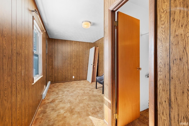 hallway featuring light carpet, a baseboard heating unit, and wood walls