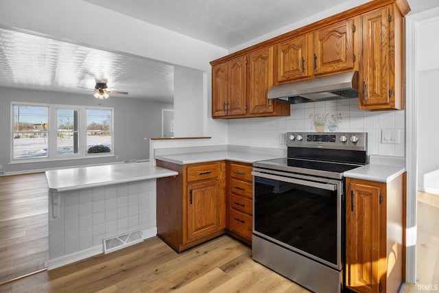 kitchen with brown cabinets, visible vents, light countertops, electric range, and extractor fan