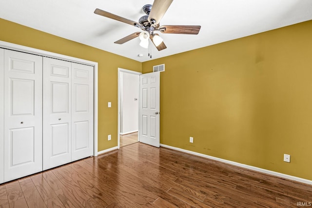 unfurnished bedroom featuring a closet, visible vents, a ceiling fan, wood finished floors, and baseboards