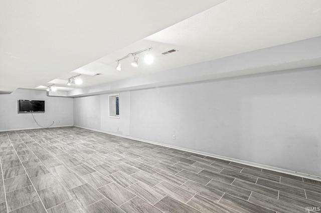 finished basement featuring rail lighting, visible vents, and baseboards