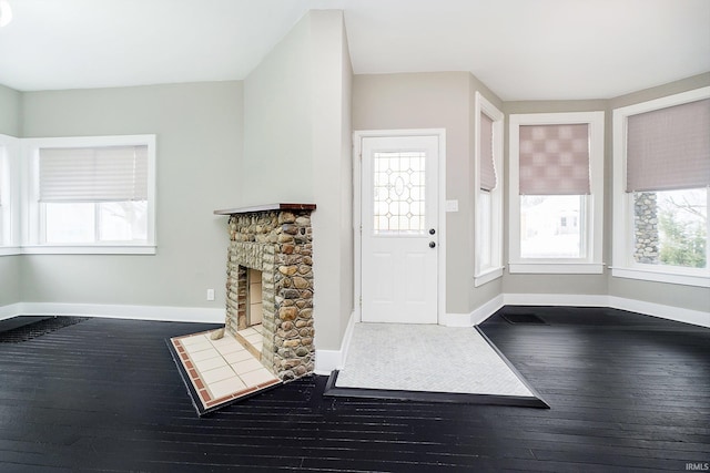 foyer entrance with dark wood-style flooring, a fireplace, and baseboards