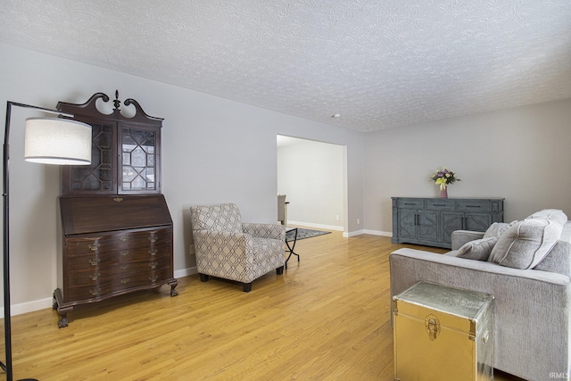 living room featuring a textured ceiling, baseboards, and wood finished floors