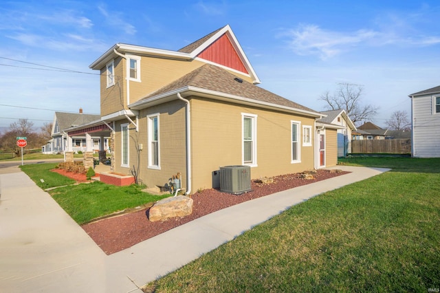 view of home's exterior featuring a lawn, covered porch, fence, central AC, and brick siding