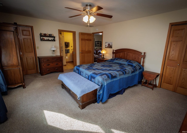 carpeted bedroom with ensuite bathroom and a ceiling fan