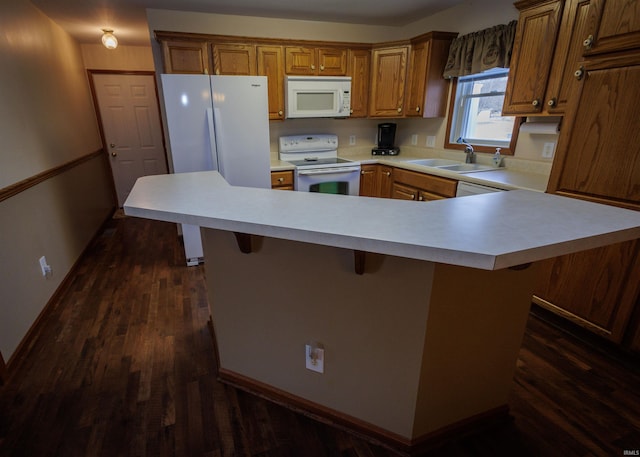 kitchen with white appliances, a sink, light countertops, brown cabinetry, and a kitchen bar