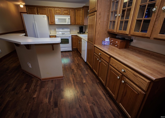 kitchen with white appliances, dark wood-type flooring, light countertops, a center island, and brown cabinetry