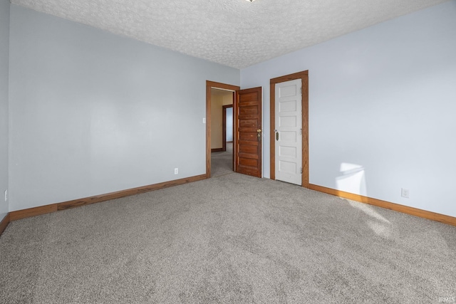 spare room with carpet, baseboards, and a textured ceiling